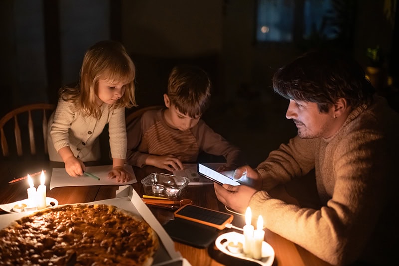 Power Outage Safety Tips for Families With Children. Photo of a family sitting at home with candles during a power outage.