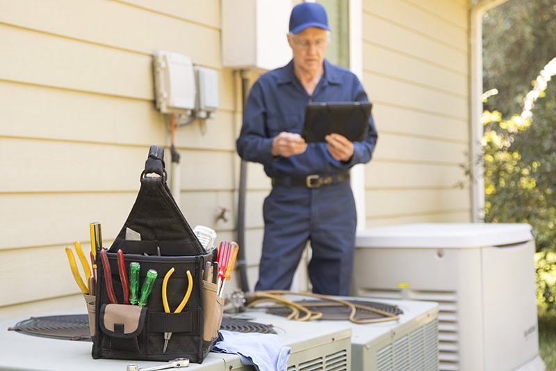 Senior Adult air conditioner Technician/Electrician services outdoor AC unit and the Gas Generator.